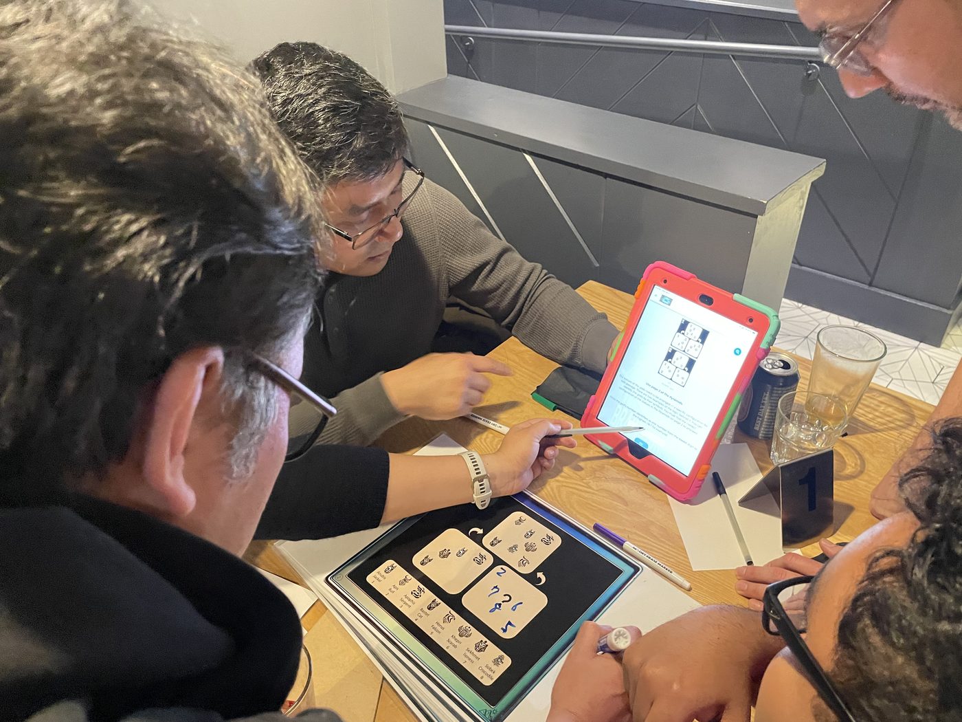 Investigators work on a real tabletop puzzle with clues on an iPad